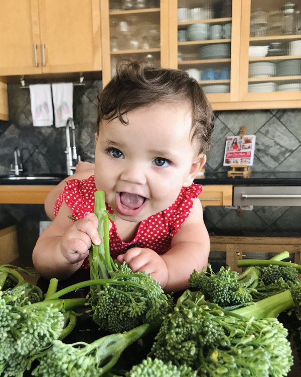 Cayenne as a baby, grinning over a pile of broccoli